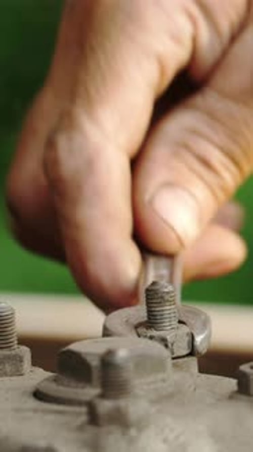 Fixing Machinery with a Wrench in a Workshop During the Day