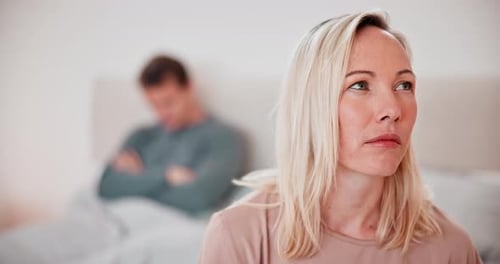 Sad Woman Sitting with Man Blurred in Background