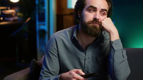 Close Up of Bored Man Sitting on Couch Flipping Though TV Channels