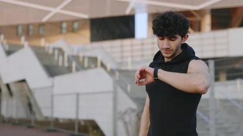 Athletic Young Adult Checks Smart Watch Outside