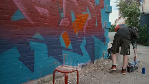 Artista caucasiano masculino desenhando forma de seta em etiqueta de grafite