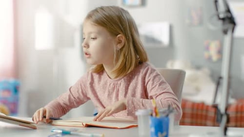 Blond Girl Writing in a Notebook at Home