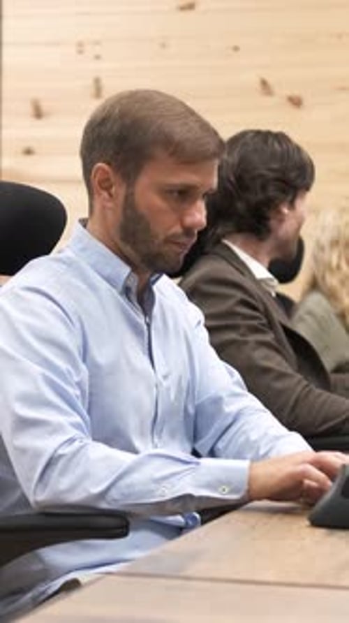 Businessman Actively Typing on a Laptop While Collaborating During a Meeting with Colleagues