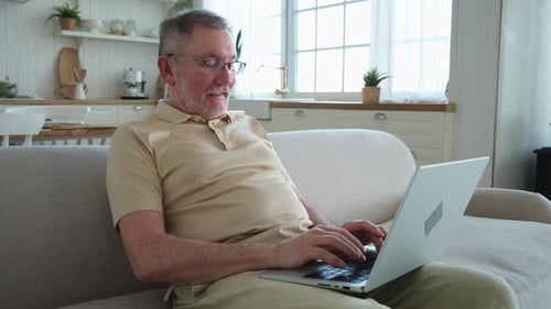 Mature Man Using Laptop on Couch at Home