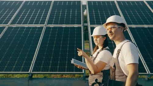 Two Technicians Lady and Guy They Walking Through the Solar Panels Rows