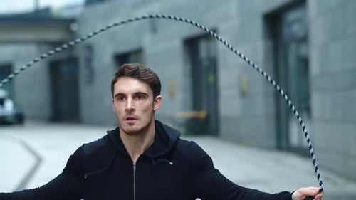 Sporty Man Jumping on Skipping Rope on City Street. Closeup Focused Guy