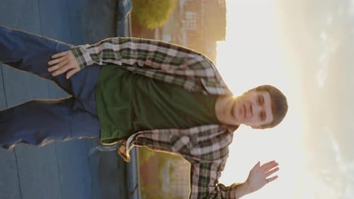 Vertikales Video Kaukasischer männlicher gutaussehender Tänzer, der bei Sonnenuntergang draußen auf dem Dach Hip Hop aufführt