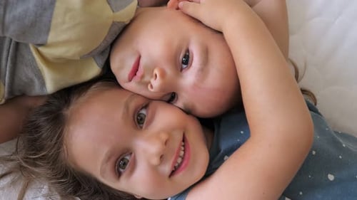 Top View Portrait of Happy Laughing Two Children Sister and Brother Lying Head to Head on the