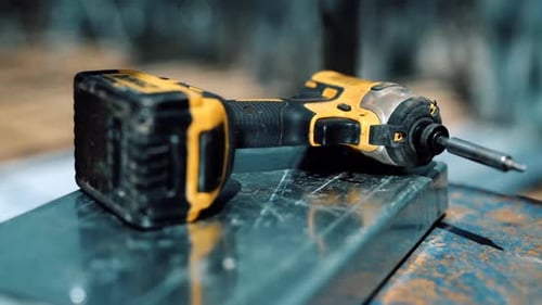 Handheld Cordless Drill On Stainless Steel Square Bar. - close up