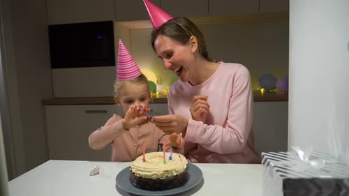 Mother and Child Preparing Birthday Cake Indoors