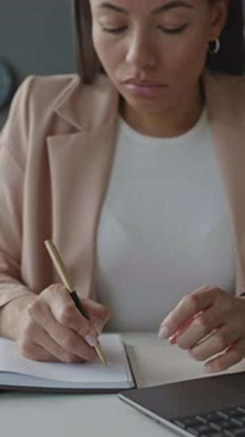 Focused Woman Works at Desk with Laptop and Notebook
