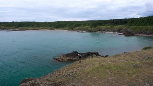 Woman at a scenic rocky shore surrounded by turquoise sea waters