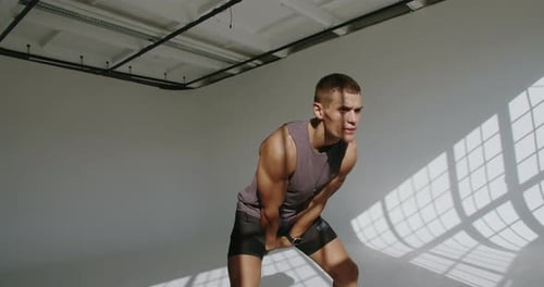 Man Doing Kettlebell Swings in Bright Room