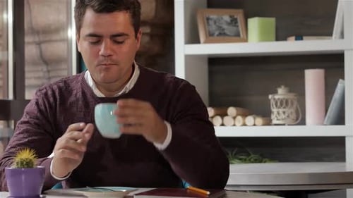 Thoughtful Man Gently Touches His Coffee Cup at a Cozy Cafe