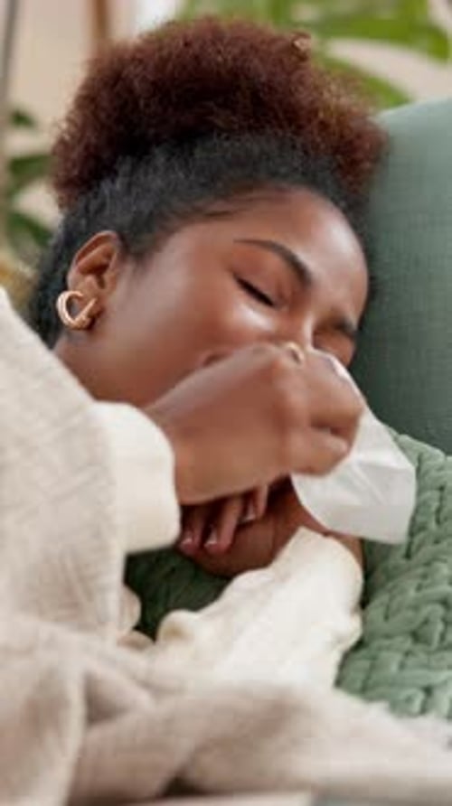 Woman Resting Indoors Blows Nose While Sick