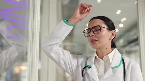 Tired Woman Doctor Leaning Against Glass Wall