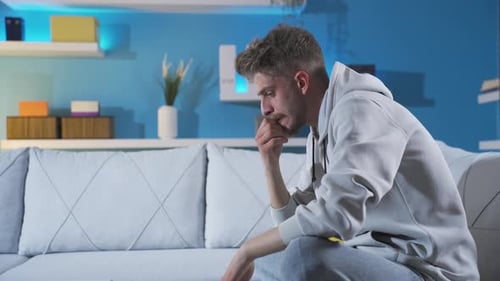 Worried Man Sitting on Couch in Living Room