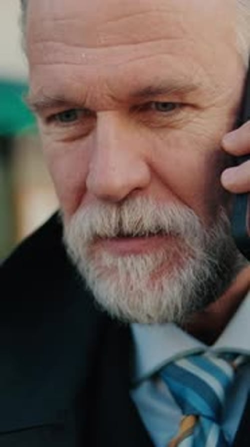 Vertical video, Mature Businessman Talking on Cell Phone in City