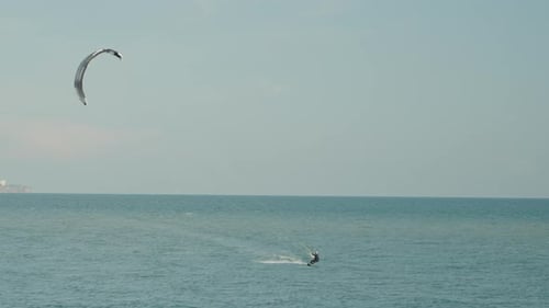 A man engages in kite surfing, jumping across the waves in the sea.