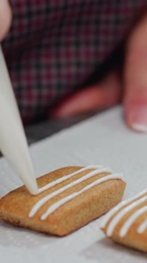 Baker Deko-Keks mit weißen Zuckergusslinien und sauber gepflegten Nägeln