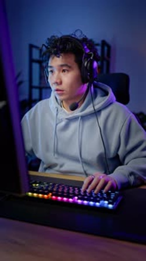 Man Gaming on Computer with Headset at Night