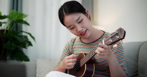 Woman Playing Ukulele on Couch at Home