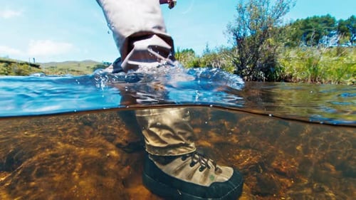 Angler Walks in the River in Wading Boots