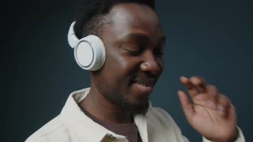 Black Man Enjoying Music in Headphones on Studio Background