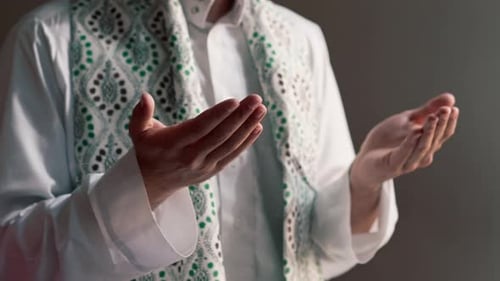 Close-up shot of a Muslim man's hands praying on his knees during Ramadan in Islamic temple