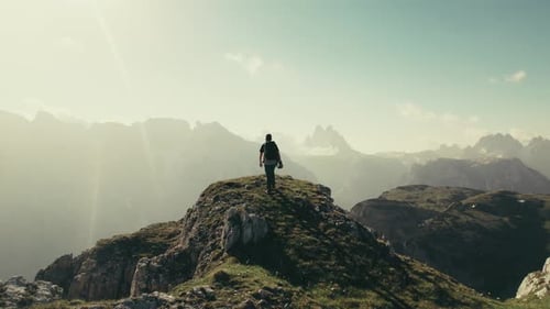 A male hiker on a hill in the mountains during sunrise. The Dolomites in South Tyrol. Slow panning f