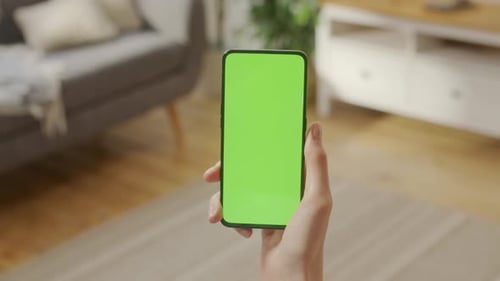 Back View of Woman Holding Chroma Key Green Screen Smartphone Watching Content Without Touching or