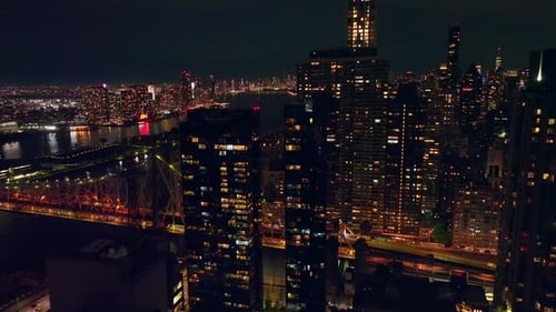 Light in the windows of the buildings in New York. Bridge over the dark river and metropolis skyline