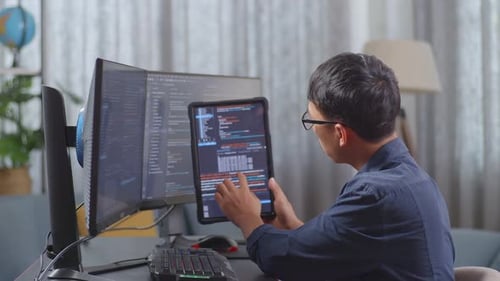 Un jeune programmeur asiatique regarde une base de données sur une tablette tout en créant une Appli de développement d'un ingénieur logiciel