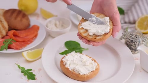 Spreading Cream Cheese on a Toasted Bun