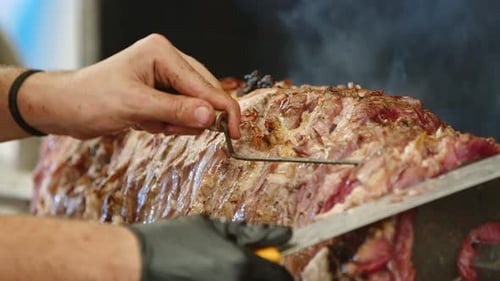 Chef Carving Roasted Meat on Spit Close Up