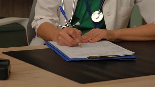 Nahaufnahme einer Allgemeinärztin, die das medizinische Formular in der Klinik ausfüllt