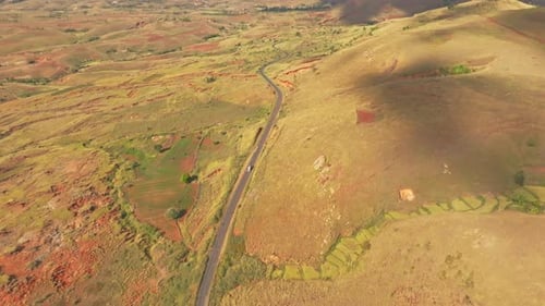 Wide angle aerial top down view of van car driving on asphalt road in Madagascar countryside on sunn