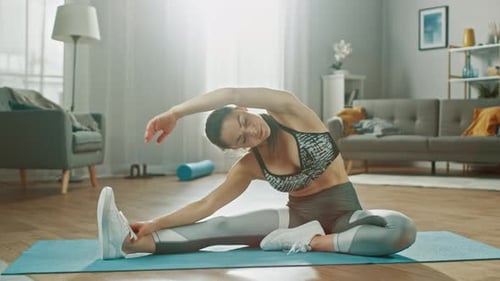 Active woman stretching on yoga mat in living room