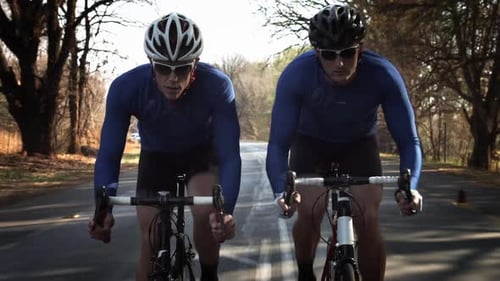 Steadicam de deux hommes en bonne santé faisant du vélo de route avec vitesse