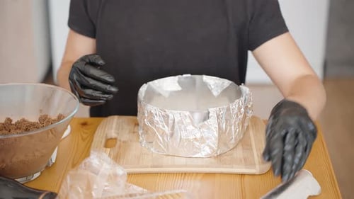 Adjusting the Foil Around the Cake Ring, Securing it on a Wooden Board. The Preparation Reflects