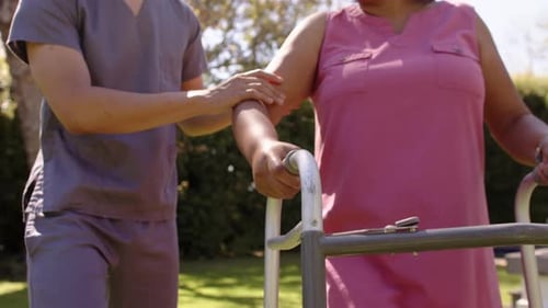 Adult Helping Senior Woman Use Walker Outside