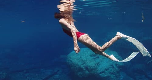Sexy Freediver Woman with Diving Fins Swims in Transparent Blue Lake Underwater View in Sunny Day