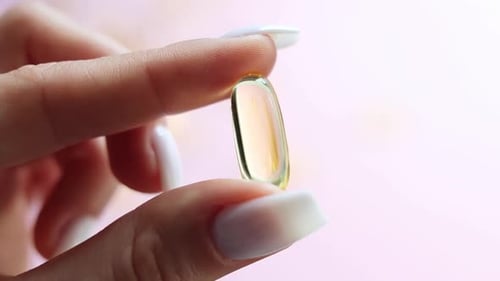 Clear Gel Pill Held Between Fingers