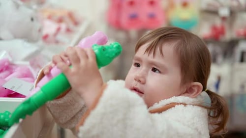 Cute 3-Year-Old Girl Amazed With Croc Plastic Toys In A Shopping Mall. - Closeup