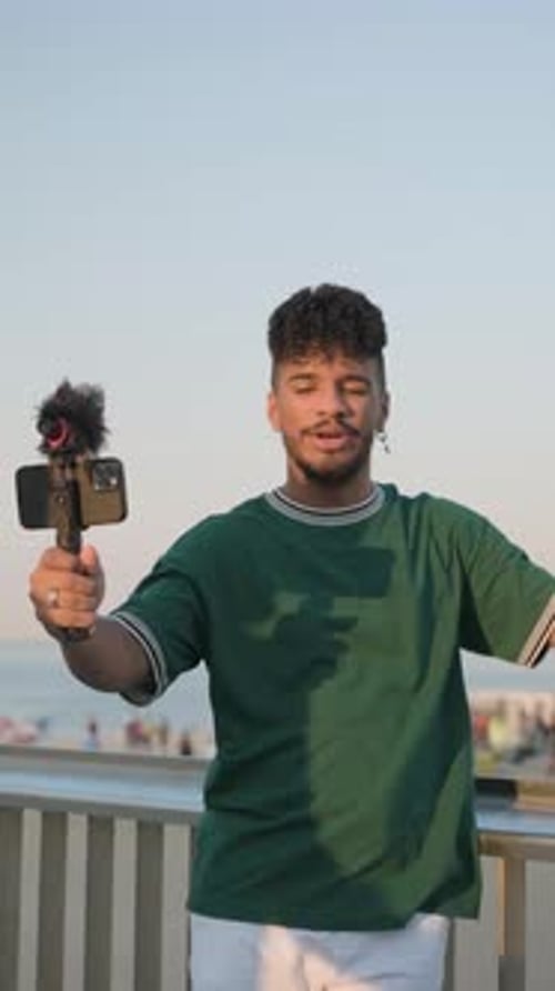 Junger Influencer nimmt ein Video mit Handy und Mikrofon auf und erstellt gleichzeitig Inhalte für sein