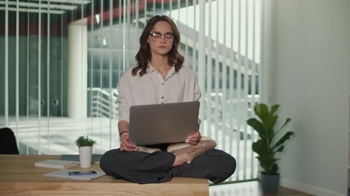 Woman Meditating with Laptop on Office Desk