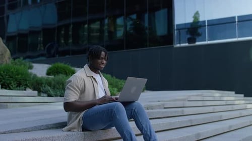 Man Working on Laptop on City Building Steps