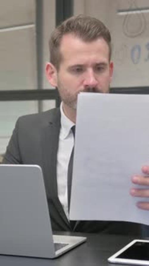 Professional Man Working at Desk with Laptop and Documents