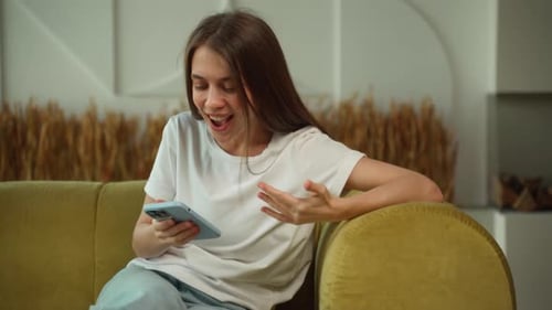 Woman Gets Good News on Phone, Celebrates on Couch