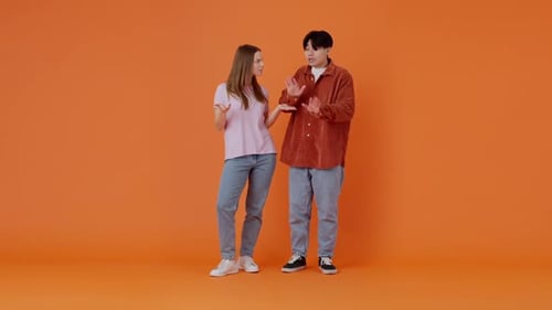 Frustrated Couple Arguing on Orange Background